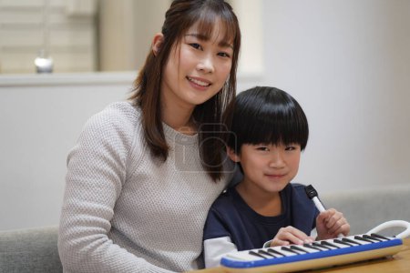 Photo for Parents and children practicing keyboard harmonica - Royalty Free Image