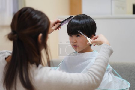 Téléchargez les photos : Mother cutting child's hair - en image libre de droit