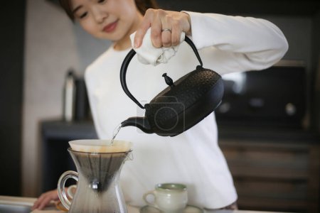 Photo for A woman brewing coffee in an iron kettle - Royalty Free Image