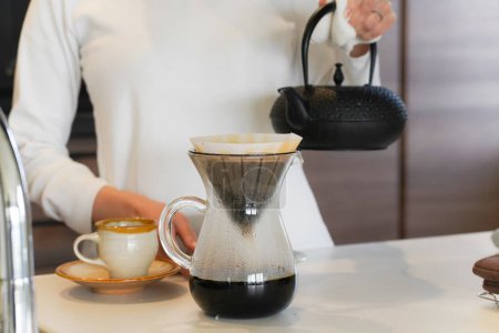 Téléchargez les photos : Une femme brassant du café dans une bouilloire en fer - en image libre de droit