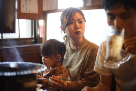 Téléchargez les photos : Parent et enfant mangent dans un restaurant Yakiniku - en image libre de droit