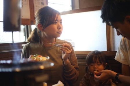 Téléchargez les photos : Parent et enfant mangent dans un restaurant Yakiniku - en image libre de droit