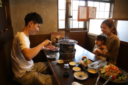 Foto de Padres e hijos comiendo en un restaurante Yakiniku - Imagen libre de derechos