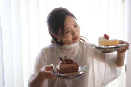 Téléchargez les photos : Une femme se demande quel gâteau manger - en image libre de droit