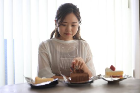 Téléchargez les photos : Une femme se demande quel gâteau manger. - en image libre de droit