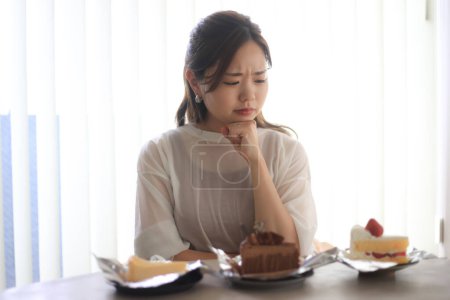 Téléchargez les photos : Une femme se demande quel gâteau manger. - en image libre de droit