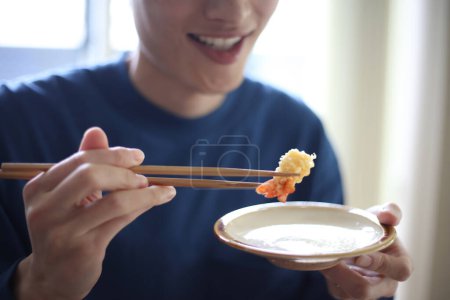 Téléchargez les photos : Un homme mangeant des crevettes tempura queue - en image libre de droit