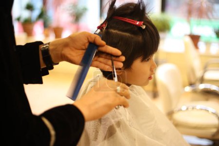 Téléchargez les photos : Homme coiffeur coupe les cheveux du garçon - en image libre de droit