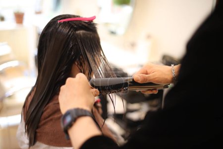 Photo for Male hairdresser applying curling iron to woman's hair - Royalty Free Image