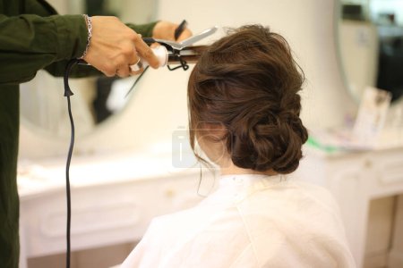 Foto de Peluquería masculina aplicando rizador al cabello de la mujer - Imagen libre de derechos