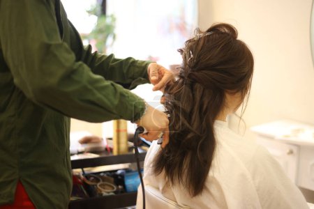 Téléchargez les photos : Coiffeur masculin appliquant du fer à friser sur les cheveux de la femme - en image libre de droit