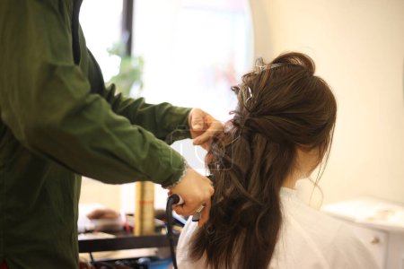 Photo for Male hairdresser applying curling iron to woman's hair - Royalty Free Image
