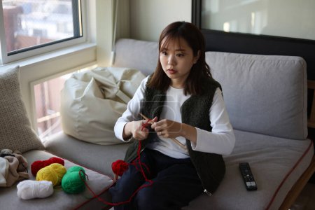Une femme tricote en regardant une vidéo