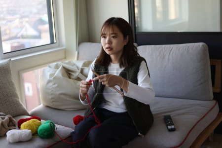 A woman knitting while watching a video