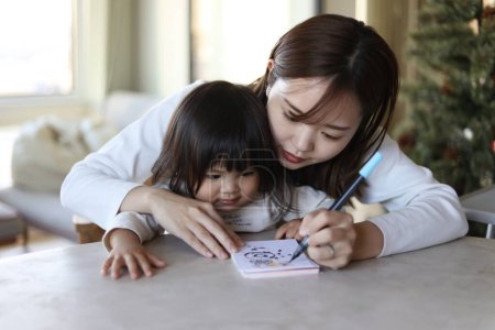 Téléchargez les photos : Les parents et les enfants qui écrivent les cartes du Nouvel An - en image libre de droit