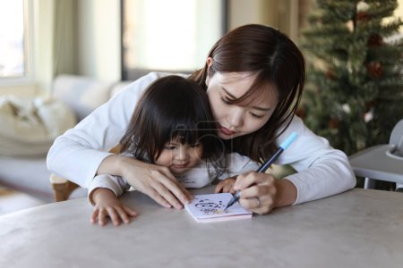 Téléchargez les photos : Les parents et les enfants qui écrivent les cartes du Nouvel An - en image libre de droit