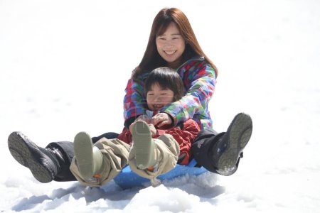 Téléchargez les photos : Parent et enfant jouant sur un traîneau - en image libre de droit