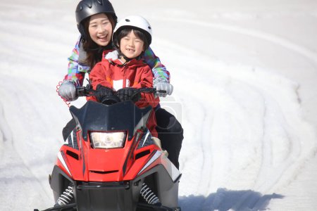 Parent and child riding a snowmobile