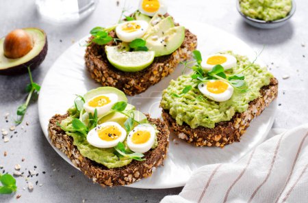 Photo for Avocado and Quail Egg Toasts, Healthy Snack or Breakfast on Bright Background - Royalty Free Image