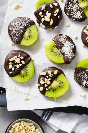 Photo for Kiwi Coved In Chocolate with Shredded Coconut and Nuts, Healthy Snack on Bright Background - Royalty Free Image