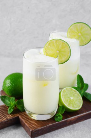 Brasilianische Limonade, erfrischende cremige Limonade oder Limeade mit Limettenscheiben und Minze auf hellem Hintergrund