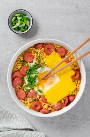 Photo for Ramen Noodles with Sausages, Egg, Melted Cheese and Scallion, Microwave Shin Ramyeon or Ramyun,Korean Noodles on Bright Background - Royalty Free Image