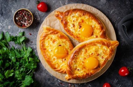 Ajarian Khachapuri, filled with cheese and topped with egg yolk, traditional Georgian Khachapuri with cheese-filled bread on Dark Rustic Background