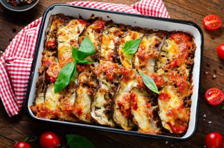 Photo for Eggplant Casserole, Roasted Eggplant Dish with Minced Meat, Tomato Sauce and Mozzarella over Wooden Background - Royalty Free Image