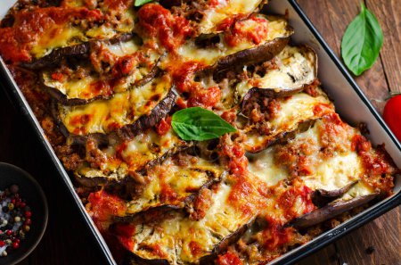 Photo for Eggplant Casserole, Roasted Eggplant Dish with Minced Meat, Tomato Sauce and Mozzarella over Wooden Background - Royalty Free Image
