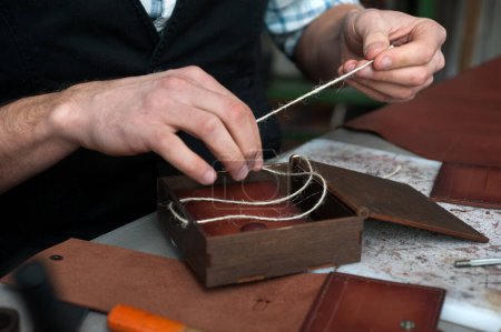 Foto de Una caja de madera para el embalaje de productos acabados de cuero hechos a mano. El artesano prepara una caja hecha a mano. Pequeñas empresas, fábricas - Imagen libre de derechos