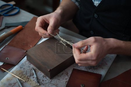 Foto de Una caja de madera para el embalaje de productos acabados de cuero hechos a mano. El artesano prepara una caja hecha a mano. Pequeñas empresas, fábricas - Imagen libre de derechos