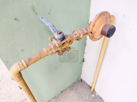 Old ball water valve and yellow painted metal pipes used on home and industrial plumbing
