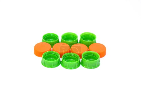 Mehrere grüne und orangefarbene Plastikflaschenverschlüsse auf weißem Hintergrund.