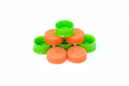 Pile of green and orange color plastic bottle lids isolated on white background.