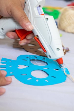 female hands holding a silicone gun gluing a craft to decorate on the day of the dead