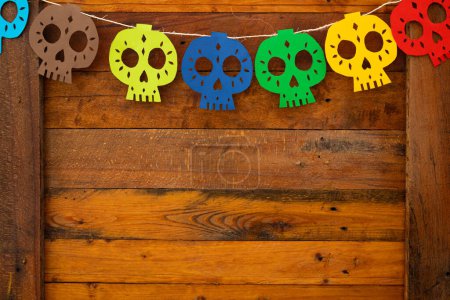 décoration de crânes de différentes couleurs en papier sur un fond en bois