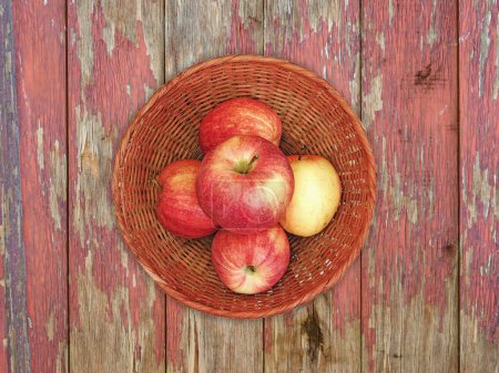 Foto de Vista superior de manzanas maduras frescas en canasta de mimbre sobre fondo de madera - Imagen libre de derechos