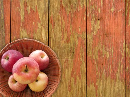Foto de Vista superior de manzanas maduras frescas en canasta de mimbre sobre fondo de madera - Imagen libre de derechos