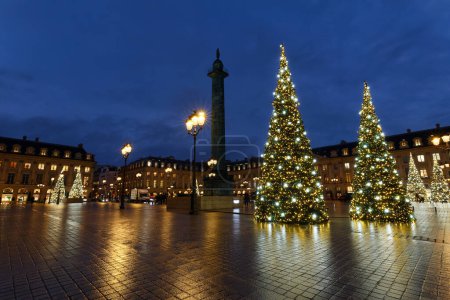 Vendome column with statue of Napoleon Bonaparte, on the Place Vendome decorated for Christmas at rainy night , Paris, France. Vendome column has 425 spiraling bas-relief bronze plates were made out of cannon.