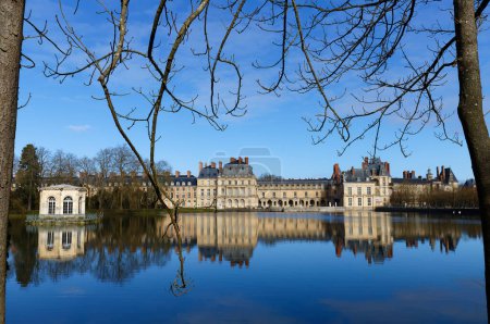 Photo for Beautiful Medieval landmark - royal hunting castle Fontainbleau with reflection in water of pond. Palace of Fontainebleau - one of largest royal castles in France, UNESCO World - Royalty Free Image