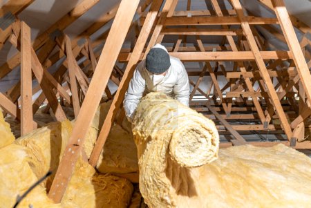 Photo for A man insulates the roof and ceiling of the house with glass wool - Royalty Free Image