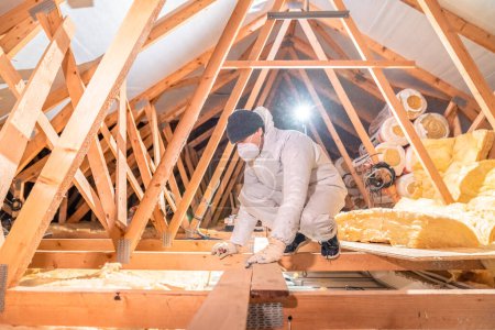 Foto de Un hombre aísla el techo y el techo de la casa con lana de vidrio - Imagen libre de derechos