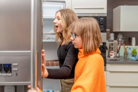 Photo for The children are watching the fridge in the kitchen. High quality photo - Royalty Free Image