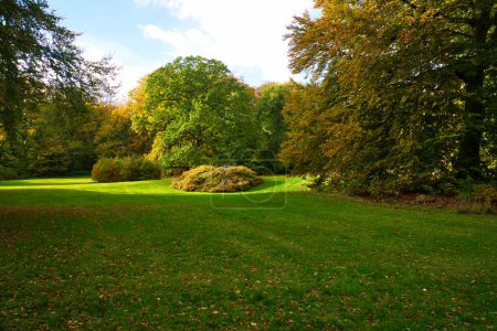 Frederiksborg Castle Park in autumn with mighty deciduous trees on the garden meadows. Colorful colors of the leaves. Walk in Denmark