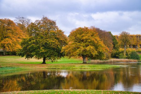 Frederiksborg Castle Park en automne avec de puissants arbres à feuilles caduques, ils se reflètent dans le lac créé. Couleurs vives des feuilles. Promenade au Danemark