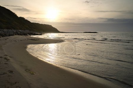 Sunset on sandy beach in Denmark by the sea. Coastal landscape in the evening hour. Landscape photo from ocean