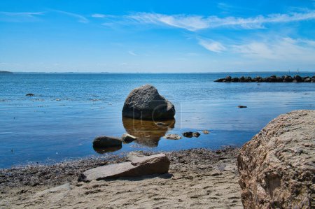 Photo for Single rock in the sea with grass. The stone lies in the Baltic Sea in sunshine. Landscape shot from German nature - Royalty Free Image