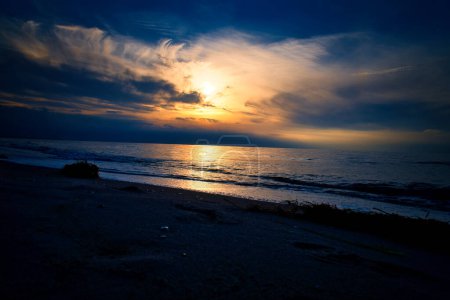 Sunset, illuminated sea. Sandy beach in the foreground. Light waves. Baltic Sea. Landscape on the coast