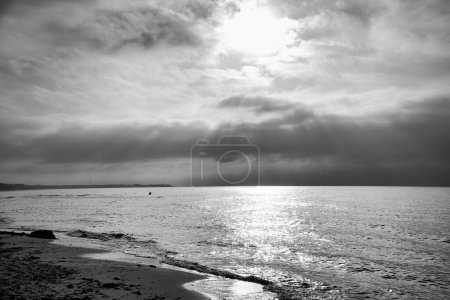 Sunset at the sea in black and white dreamy. Sandy beach in the foreground. Gentle waves. Baltic Sea. Landscape on the coast