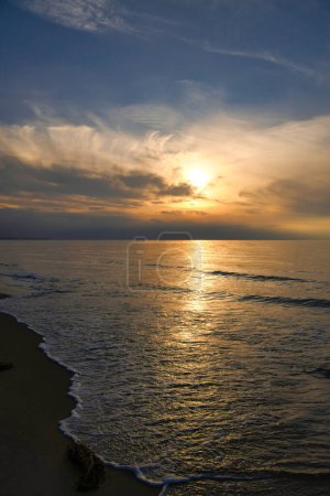Puesta de sol, mar iluminado. Playa de arena en primer plano. Ondas de luz. Mar Báltico. Paisaje en la costa